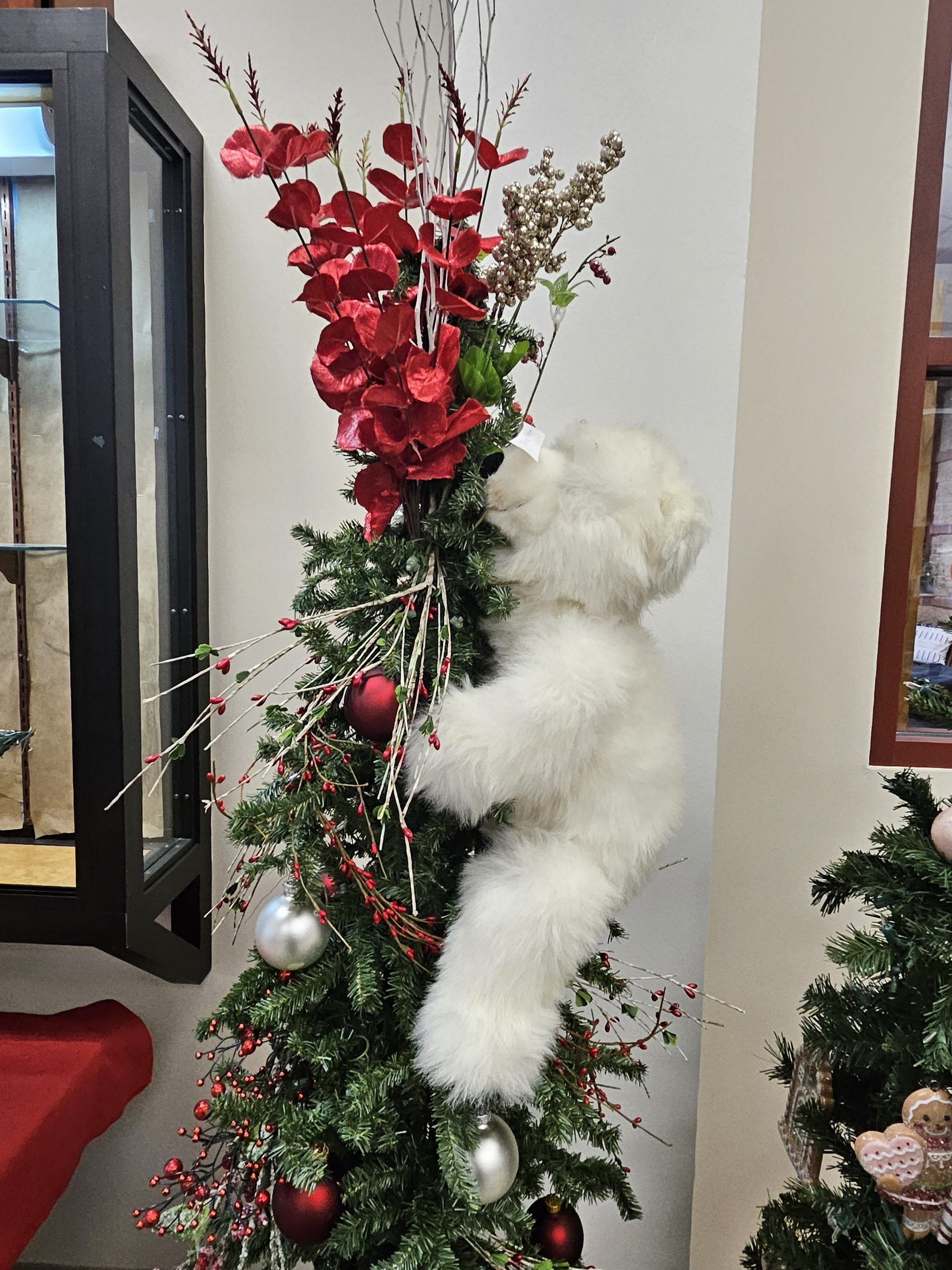 A Christmas tree with a white bear stuffed animal hugging it. 
